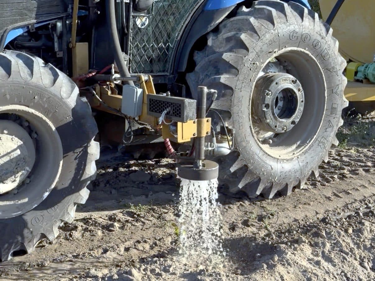 Riego automatizado de Emflora aplicando agua al suelo, con control electrónico acoplado al tractor