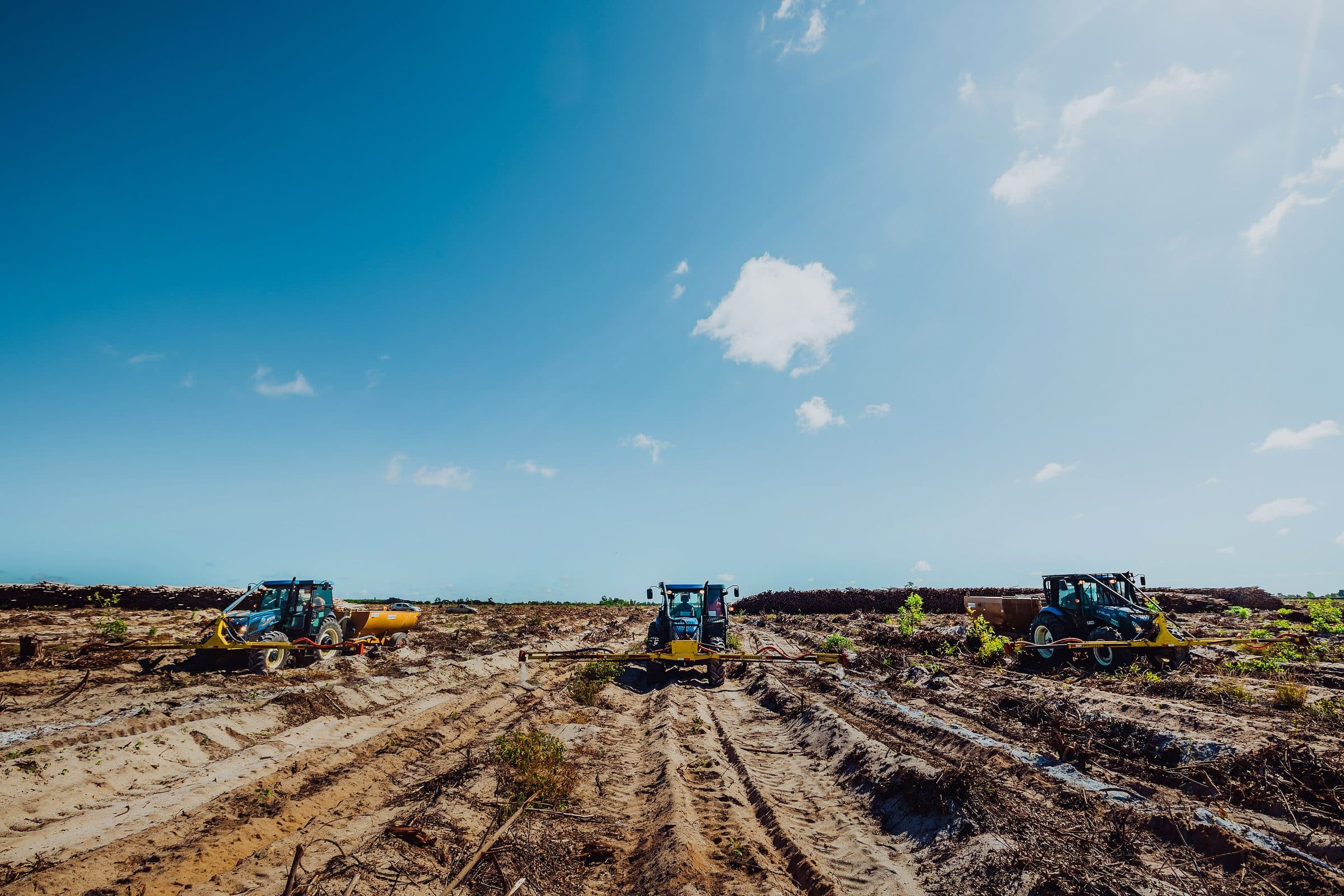 Three Emflora tractors with implements working side by side in the field