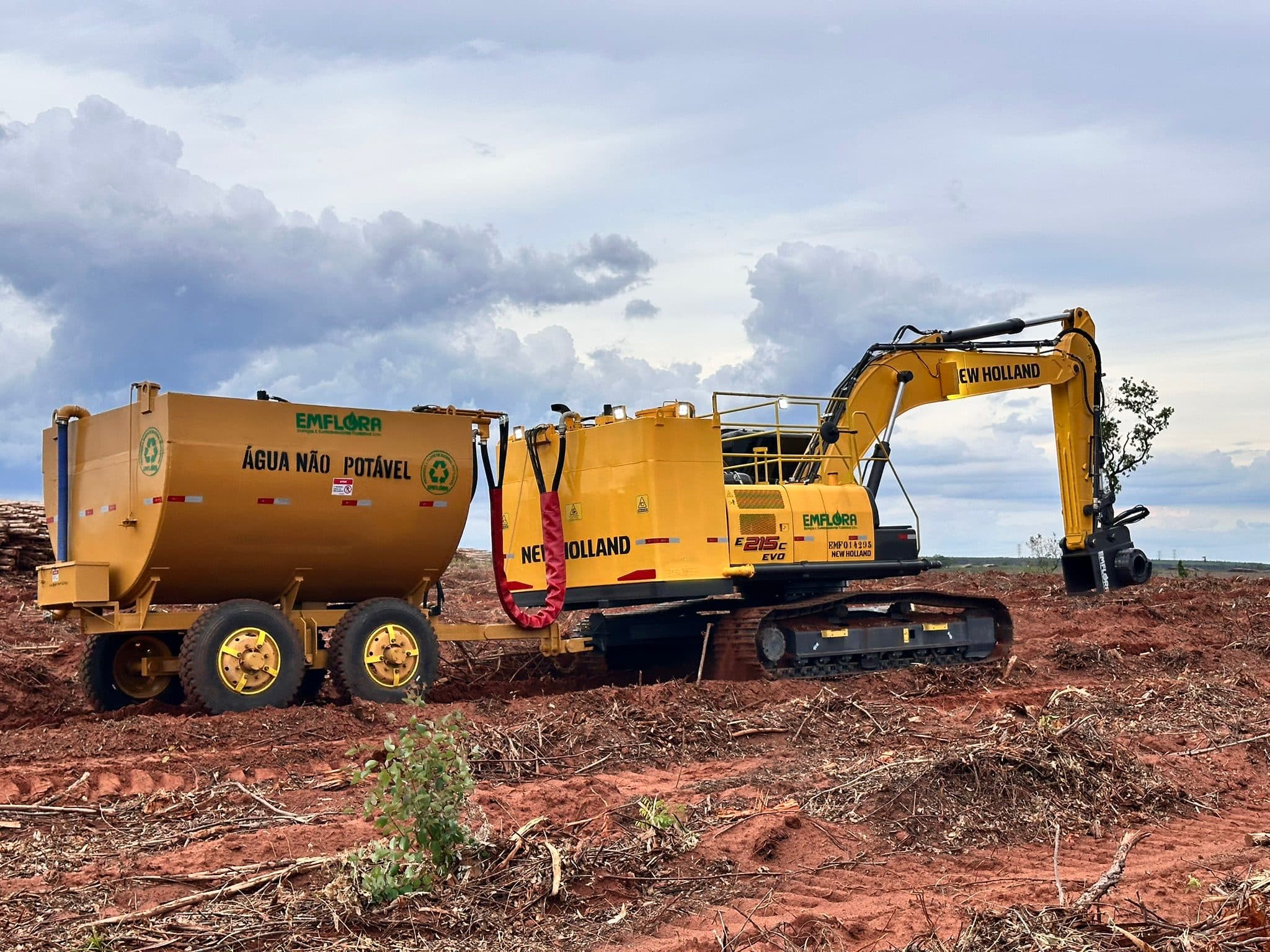 Emflora New Holland excavator towing an irrigation water tank in a forestry field